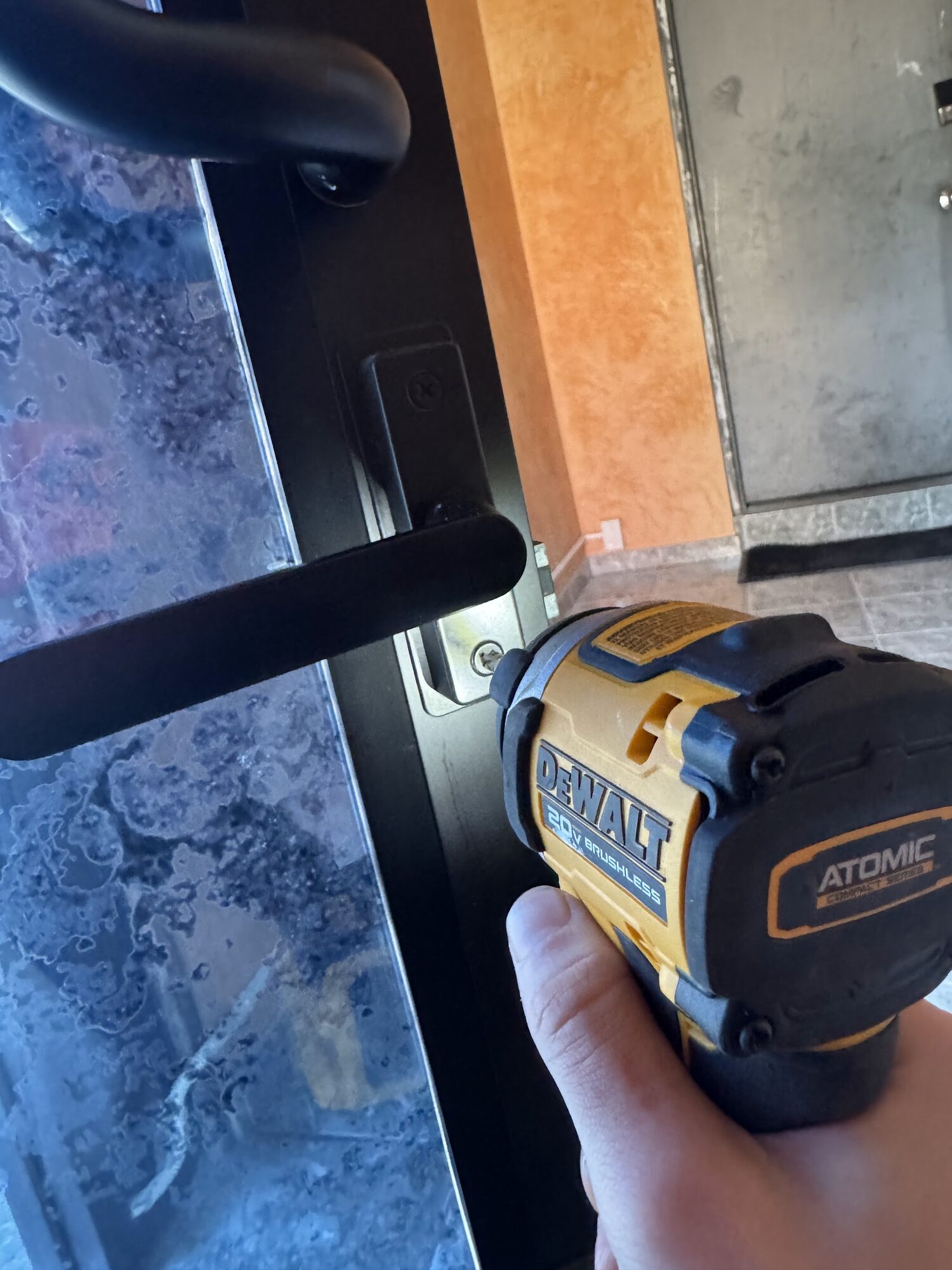 Installing a lever handle on a glass storefront door with an impact driver