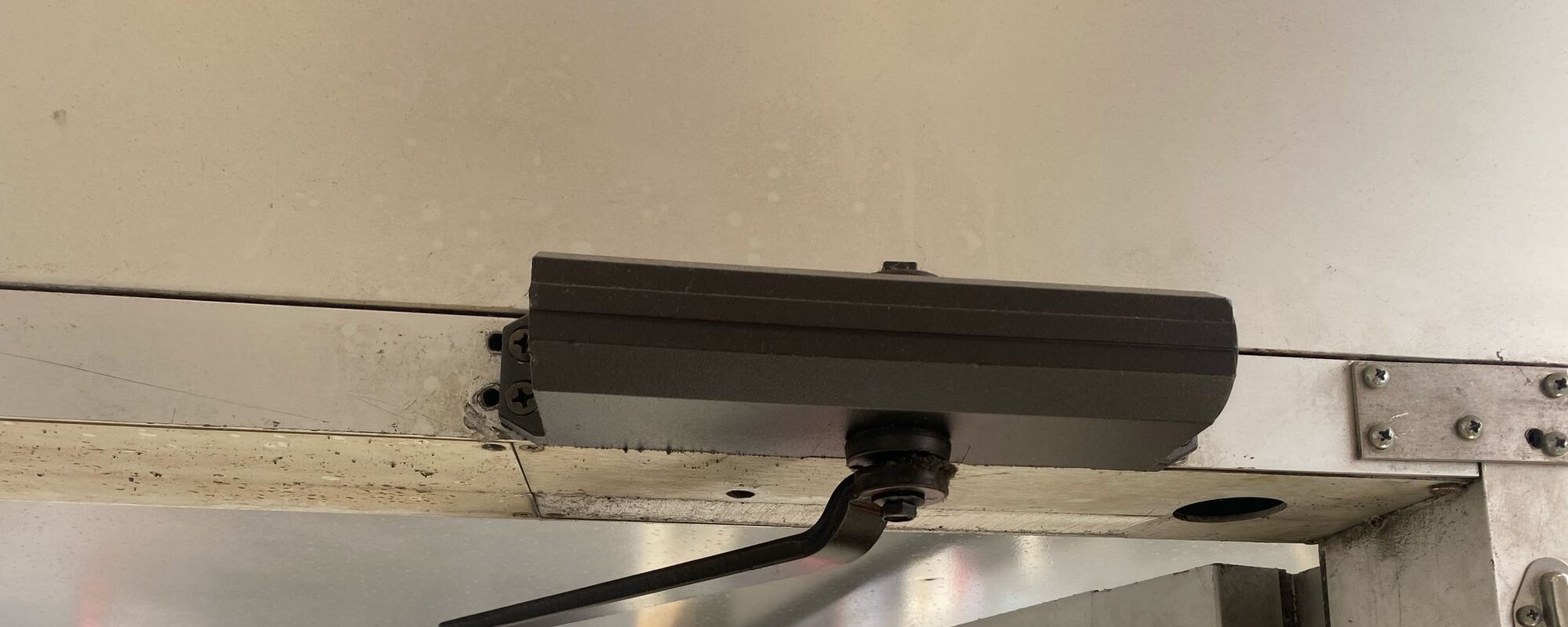 Commercial door closer mounted on a stainless storefront door frame